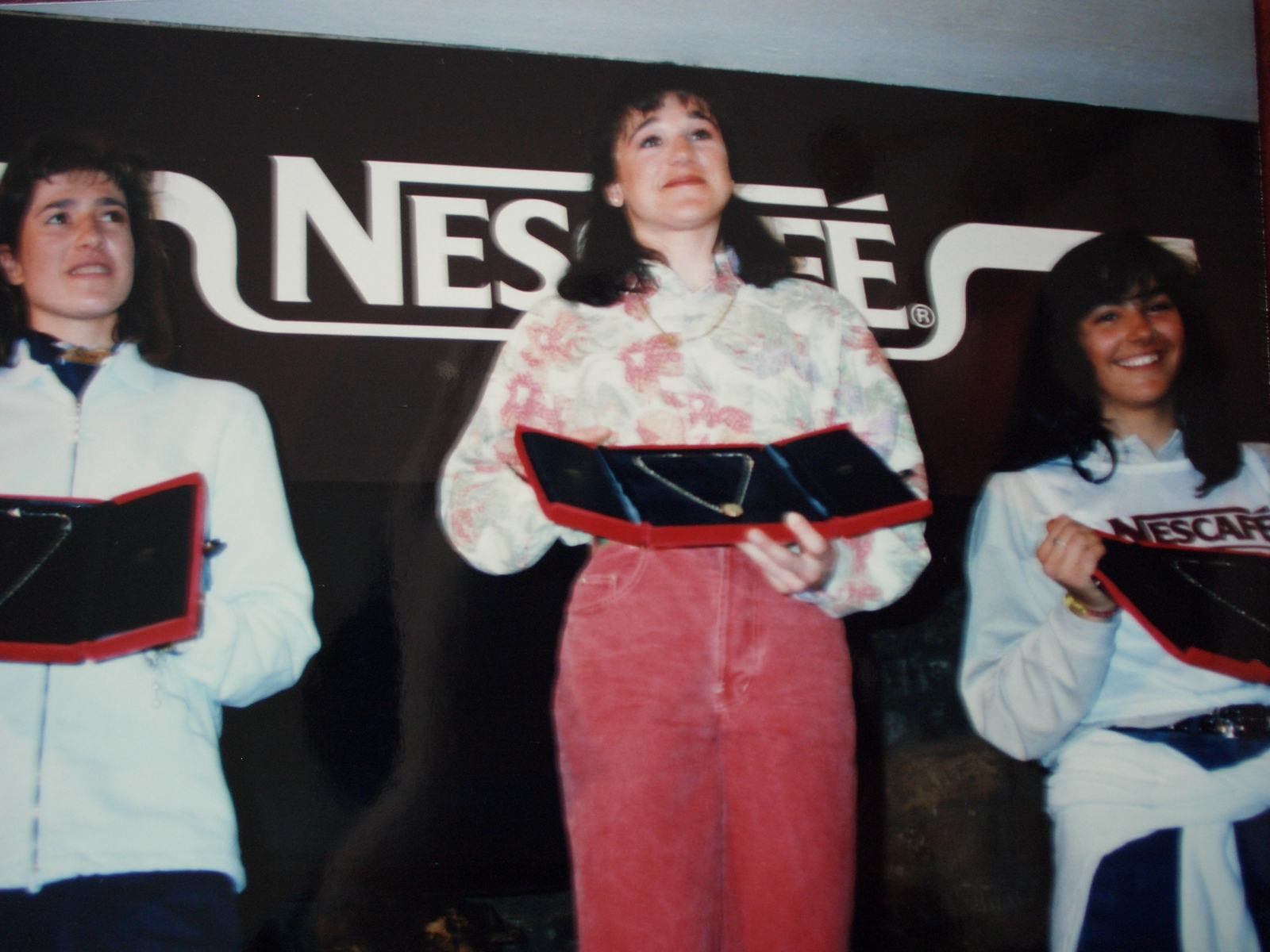 Tres jóvenes esquiadoras en el podio de un trofeo patrocinado por Nescafé